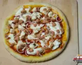 Gotowa do pieczenia pizza z tuńczykiem, mozzarellą i cebulą na drewnianej desce.