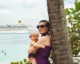 Mamma e bimbo abbracciati vicino a una palma, con una nave da crociera all'orizzonte. Una splendida posizione costa pacifica.