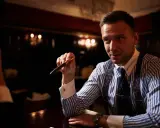 Mężczyzna w eleganckiej koszuli i krawacie trzyma pióro, zastanawiając się, ile bierze adwokat za reprezentowanie w sądzie.