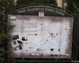 Mapa turystyczna gminy Warka z zaznaczonymi zabytkami, w tym Dworkiem na Długiej. W tle drzewa, a na dole strony logo "Warka" i adres strony.