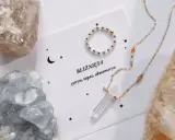 Delikatna biżuteria z kamieniami, w tym akwamaryn, otoczona surowymi kryształami.