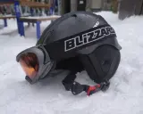 Czarny kask narciarski z goglami na śniegu.