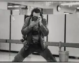 Un uomo con più macchine fotografiche al collo, intento a scattare un autoscatto. Un'immagine che cattura l'essenza di un fotografo, forse lo stesso René Burri.