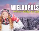 Uśmiechnięta dziewczynka w zimowym stroju pokazuje kciuki w górę na tle ośnieżonych drzew. Wielkopolska oferuje wspaniałe atrakcje dla dzieci zimą!