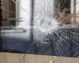 Une étoile de verre brisé se propage à travers la vitre, révélant un monde flou derrière.