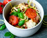 Herzhafte rezepte mit zucchini und hackfleisch: Zoodles mit Hackfleischsauce, Tomaten und geschmolzenem Käse, garniert mit frischem Basilikum.
