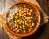 Cazuela de barro con garbanzos y espinacas, humeante y lista para servir. Se puede poner cazuela de barro en la vitro para cocinar este delicioso plato.