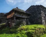 Antiguos hórreos de piedra y madera, testigos de la ruta del silencio. Hierba verde y cielo azul.
