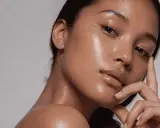 Rostro de mujer con piel glowy, hidratada y radiante. Su mano acaricia suavemente su barbilla.