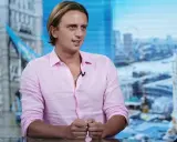 Nikołaj Storonski w różowej koszuli, na tle panoramy Londynu z Tower Bridge.