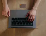 Manos sobre un portátil y una tarjeta de crédito, listo para aprender como pasar dinero de una cuenta a otra.