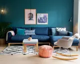 Un accogliente salotto con divano blu, tappeto a rombi e pareti color ral ottanio.