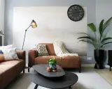 Salon moderne avec canapés marron, coussins colorés, plante verte et horloge murale. Une belle ambiance pour votre diy deco.