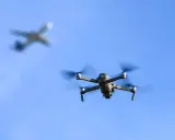 Drohne fliegt im Himmel, ein Flugzeug im Hintergrund. Wichtig: Drohne Haftpflicht für sichere Flüge.