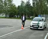 Egzamin praktyczny w WORDzie: młody mężczyzna ustawia pachołek na placu manewrowym obok białego Fiata Panda z literą L.