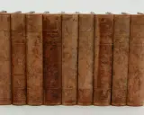 En samling böcker av Carl Grimberg, "Svenska folkets underbara öden", i åtta volymer med slitna läderomslag och guldfärgad text.