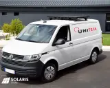 Un fourgon blanc avec un panneau solaire sur barre de toit. Le logo UNITECK est visible sur le côté.