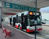 Autobus wahadłowy na przystanku lotnisko. Czerwona ławka czeka na pasażerów.