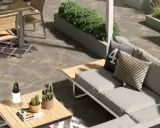 Un elegante giardino pavimentato moderno con divano, tavolo da pranzo e piante.