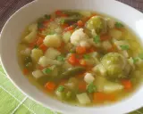 Aromaticzna jarzynowa zupa z ziemniakami, marchewką, kalafiorem i brukselką, udekorowana natką pietruszki.