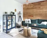 Przytulny salon z kanapą, regałem i dekoracyjnym drewnem na ścianie.