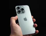 Dłoń trzyma srebrny iPhone 15 Pro z widocznym modułem aparatów i logo Apple. Dynamic Island na ekranie tego modelu to innowacja.