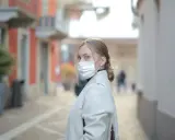 Kobieta w masce na twarzy, zastanawia się, ile można być na L4, idąc ulicą.