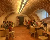 Grupa zwiedza piwnice pałacu w Poddębicach. Przewodniczka opowiada o historii miejsca.