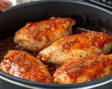 Quatre poitrines de poulet savoureuses, nappées d'une sauce rouge et saupoudrées d'épices, prêtes à être dégustées. Un délice inspiré du marinade poulet portugais.