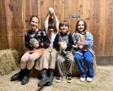Bambini felici durante un'attività fattoria, tengono in braccio coniglietti soffici.