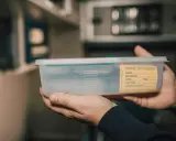 Dłoń trzyma pojemnik z próbką moczu. Niewielka ilość płynu może wskazywać na skąpomocz.