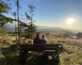 Para siedzi na ławce, podziwiając widok na Beskid Wyspowy. To z pewnością najładniejszy szlak na Mogielicę, z tak pięknym zachodem słońca.