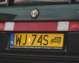 Zielona Alfa Romeo z żółtą rejestracją WJ-74S. Na tablicy widnieje symbol starego samochodu.