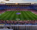 Widok na stadion Camp Nou podczas remontu, z trybunami w kolorach FC Barcelony i oświetlonym boiskiem.