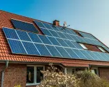 Ett tegelhus med solpaneler på taket, en del av solenergi historia.
