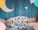 Niño duerme plácidamente en su cama, con pijama de estrellas. Es hora de acostarse y soñar con la luna y las estrellas decoran su habitación.