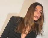 Mujer con cabello color moca y traje a rayas negras.