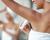 Une femme applique un déodorant sous ses aisselles. L'acide glycolique peut aider à éclaircir les aisselles.