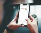 Ręce trzymające smartfon z otwartą wyszukiwarką Google. Szukasz informacji, jak usunąć konto Google z telefonu po resecie?