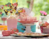 Una encantadora mesa de chuches casera con galletas de pájaros, malvaviscos y dulces en tonos pastel.
