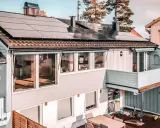 Hus med trina solceller på taket. En balkong med blommor och ett dekorativt hjul.