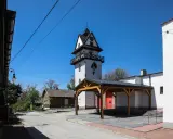 Wieża zegarowa i drewniany domek w słoneczny dzień.