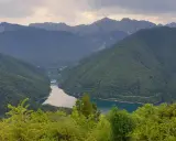 Valli boscose e un lago serpeggiante nella **Garfagnana e Lunigiana**, con montagne maestose sullo sfondo.