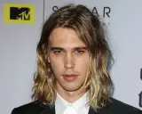 Austin Butler z długimi, falowanymi włosami, który udowadnia, komu pasują długie włosy męskie.
