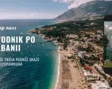 Przewodnik po Albanii, który sprawi, że Twoja podróż będzie niezapomniana. Widok na wybrzeże i góry, z telefonem prezentującym okładkę książki o Albanii.