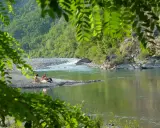 Un **lago vicino Milano con spiaggia** dove coppie si rilassano tra rocce e vegetazione lussureggiante.
