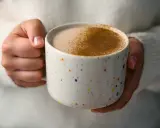 Ciepły napój w kolorowym kubku, posypany cynamonem. Czy to chai latte? Idealny na chłodne dni.