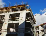 Rohbau eines Mehrfamilienhauses im Rahmen der Entwicklung von urbane gebiete. Gerüste und Betonstrukturen unter blauem Himmel.