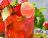 Två glas med en uppfriskande strawberry mojito, garnerade med jordgubbar, lime och mynta. Perfekt för en varm sommardag.