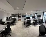 Bureau moderne avec postes de travail réglables en hauteur, écrans d'ordinateur et chaises ergonomiques. L'espace semble propre, mais on pourrait y sentir un air vicié sans fenêtres ouvertes.